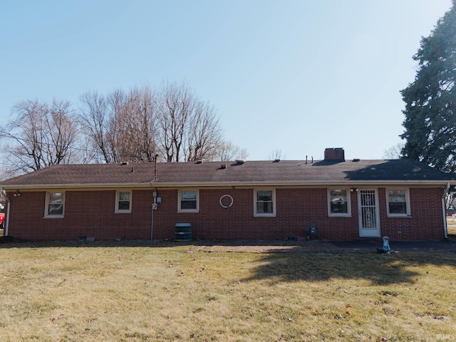 rear view of house featuring central AC unit, a lawn, brick siding, and a chimney