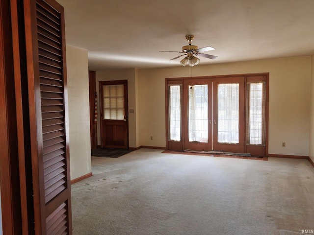 carpeted entryway featuring baseboards and ceiling fan