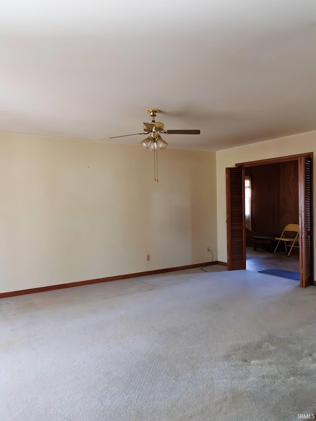 empty room featuring baseboards, carpet floors, and a ceiling fan