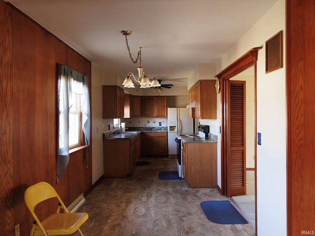 kitchen featuring dark countertops, range with electric cooktop, an inviting chandelier, and a sink