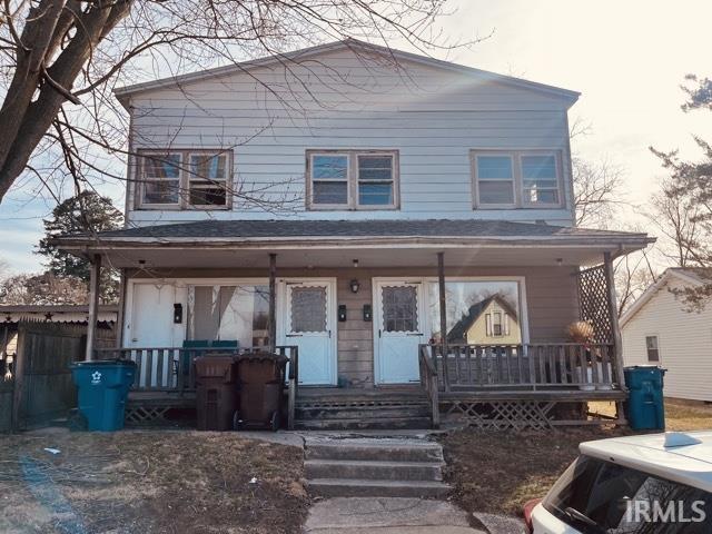 view of front facade featuring covered porch and fence