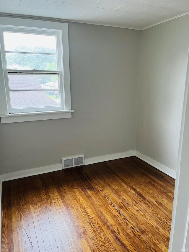 unfurnished room featuring wood finished floors, visible vents, and baseboards