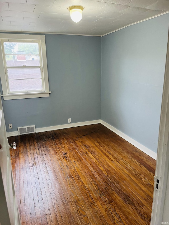 spare room featuring visible vents, baseboards, and dark wood-style flooring