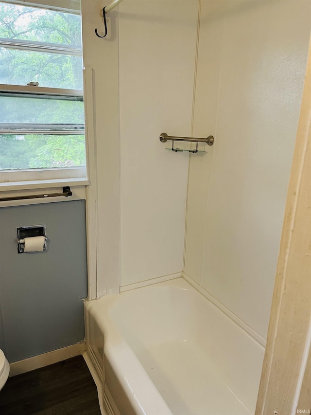 full bathroom with wood finished floors, toilet, a healthy amount of sunlight, and baseboards