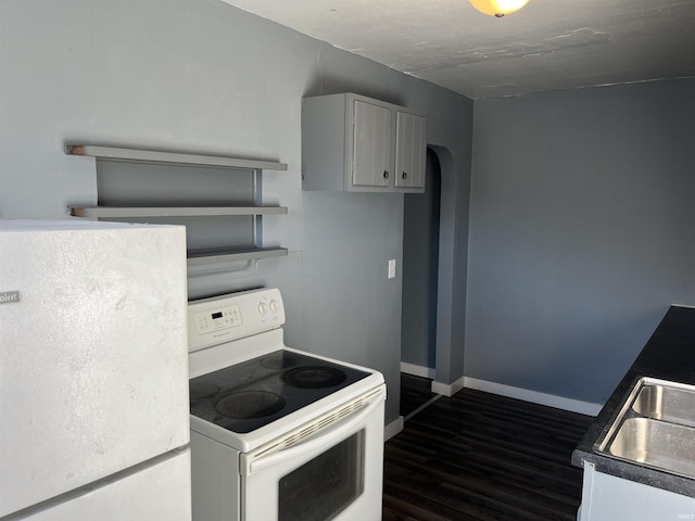 kitchen with dark wood-type flooring, a sink, white appliances, arched walkways, and baseboards