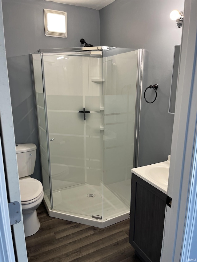 bathroom featuring a stall shower, toilet, vanity, and wood finished floors