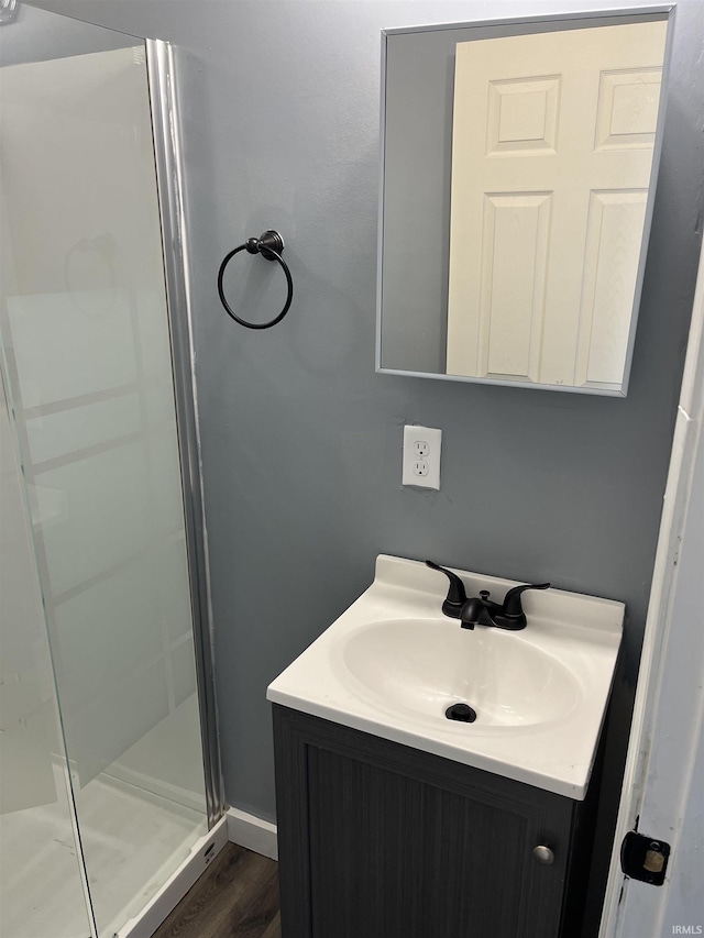 full bath featuring vanity, wood finished floors, and a stall shower