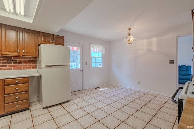 kitchen with a notable chandelier, white appliances, brown cabinetry, light countertops, and light tile patterned floors