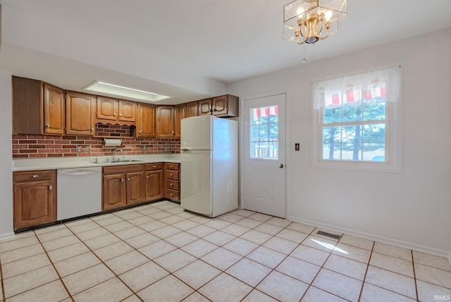 kitchen with brown cabinetry, visible vents, white appliances, and light countertops