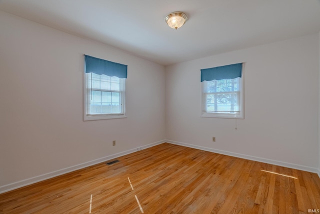 spare room with visible vents, plenty of natural light, and light wood finished floors