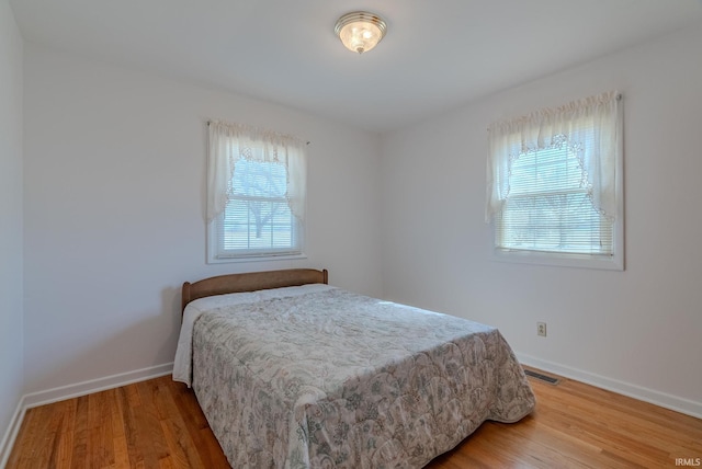 bedroom featuring visible vents, multiple windows, and wood finished floors