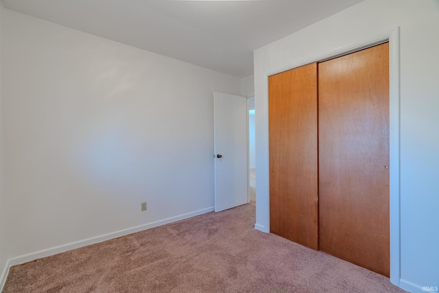 unfurnished bedroom with a closet, baseboards, and carpet