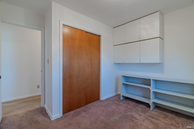 interior space featuring a closet, baseboards, and carpet