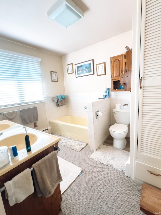 bathroom with a wainscoted wall, a garden tub, toilet, tile walls, and vanity