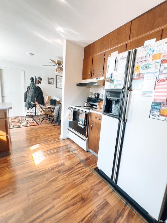 kitchen featuring under cabinet range hood, light wood-type flooring, white refrigerator with ice dispenser, electric stove, and brown cabinetry