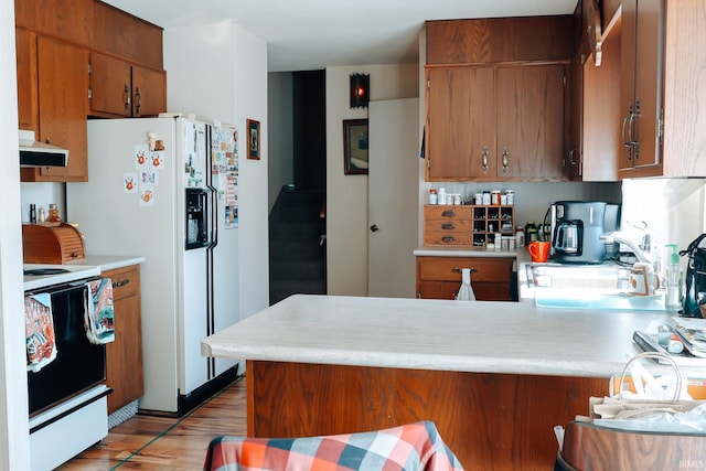 kitchen featuring under cabinet range hood, range with electric stovetop, and light countertops