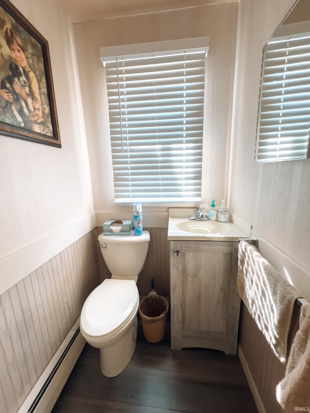 bathroom featuring vanity, wood finished floors, wainscoting, a baseboard heating unit, and toilet