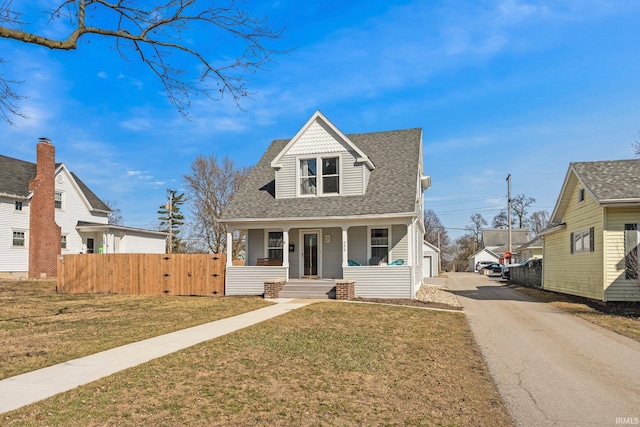 view of front of house with aphalt driveway, a porch, fence, roof with shingles, and a front yard