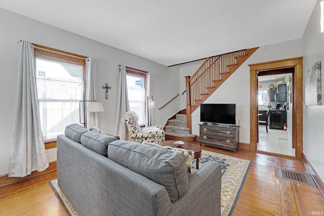 living room with visible vents, stairs, and wood finished floors