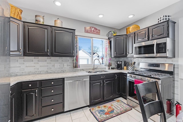 kitchen featuring a sink, light stone counters, tasteful backsplash, and stainless steel appliances