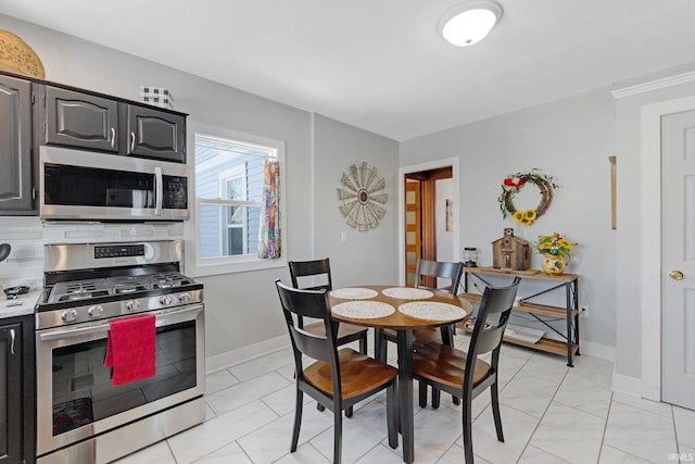 kitchen featuring backsplash, appliances with stainless steel finishes, light countertops, and baseboards