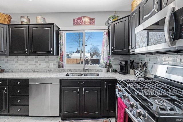 kitchen featuring a sink, dark cabinetry, decorative backsplash, and stainless steel appliances