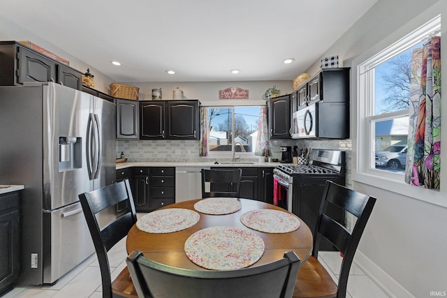 kitchen featuring light tile patterned flooring, a sink, stainless steel appliances, light countertops, and tasteful backsplash