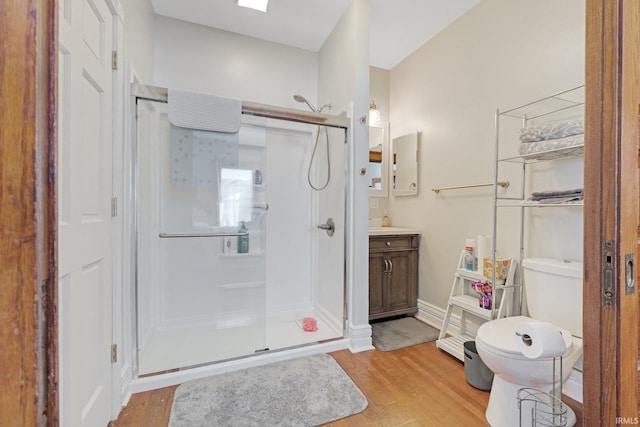 bathroom featuring vanity, a shower stall, toilet, and wood finished floors