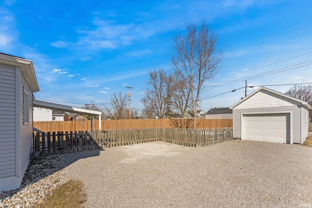 view of yard with an outbuilding, driveway, fence private yard, and a detached garage