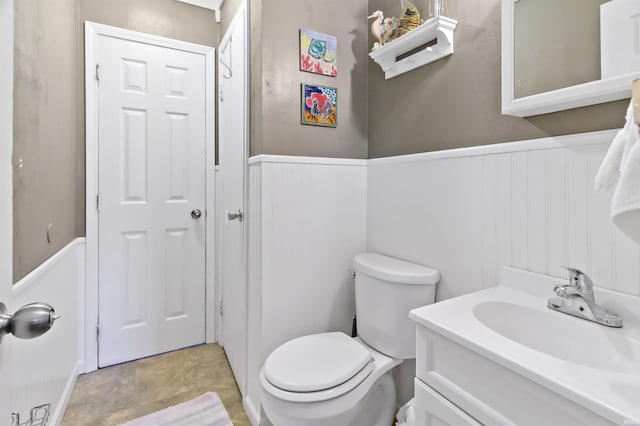 bathroom featuring vanity, toilet, and wainscoting