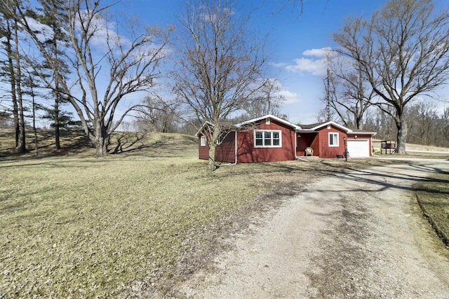 exterior space featuring an attached garage, a front yard, and dirt driveway