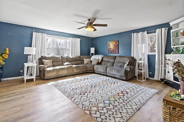 living room with baseboards, wood finished floors, and ceiling fan