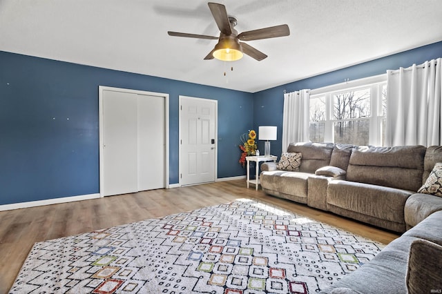 living room with baseboards, wood finished floors, and ceiling fan