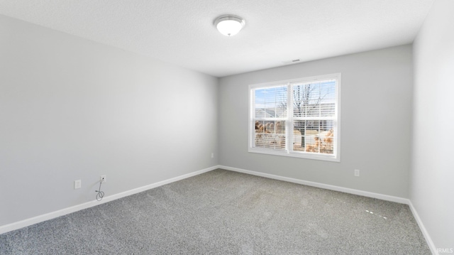 carpeted spare room with visible vents, a textured ceiling, and baseboards