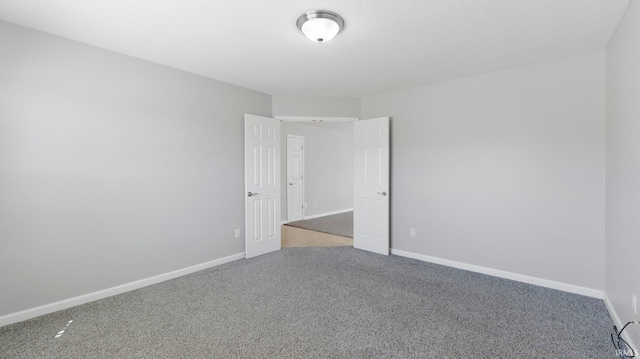 empty room with baseboards, carpet, and a textured ceiling