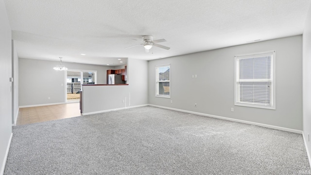 unfurnished living room with baseboards, a textured ceiling, carpet flooring, and ceiling fan with notable chandelier