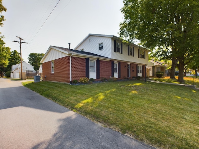 colonial inspired home featuring cooling unit, brick siding, and a front lawn