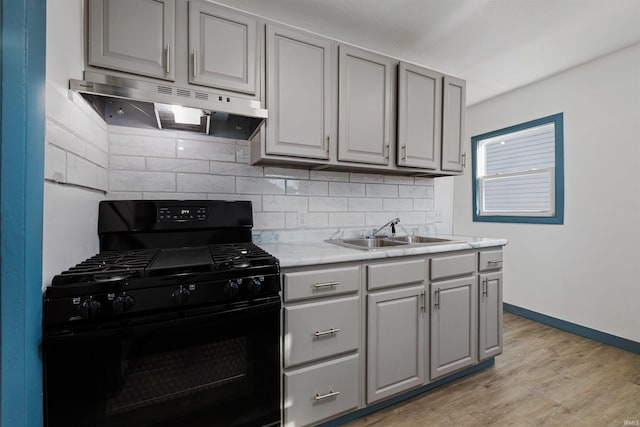 kitchen featuring under cabinet range hood, black gas range, gray cabinets, and a sink