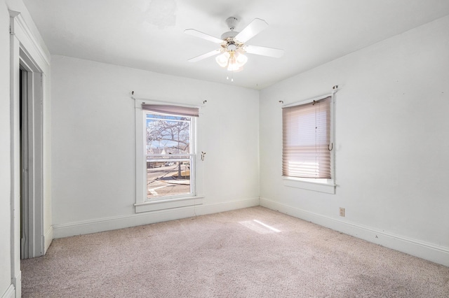 spare room with a ceiling fan, baseboards, and light carpet