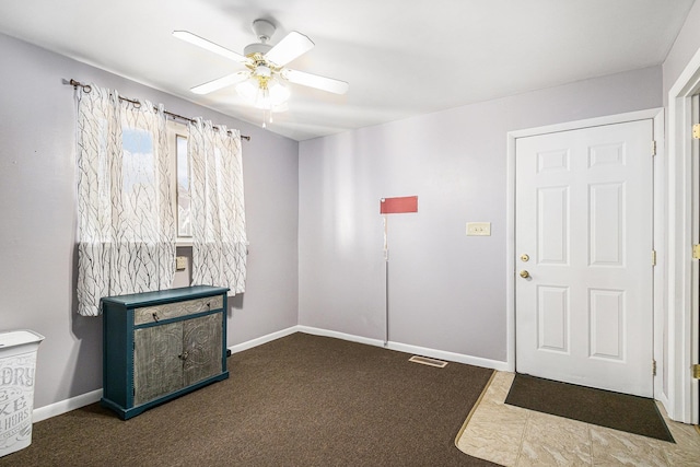 carpeted foyer with visible vents, baseboards, and a ceiling fan