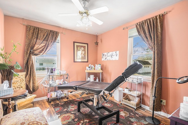 interior space with cooling unit, baseboards, wood finished floors, and a ceiling fan