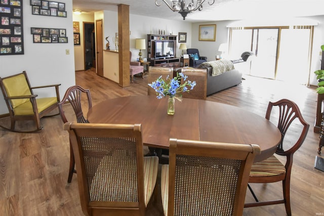 dining area featuring a notable chandelier, baseboards, and wood finished floors