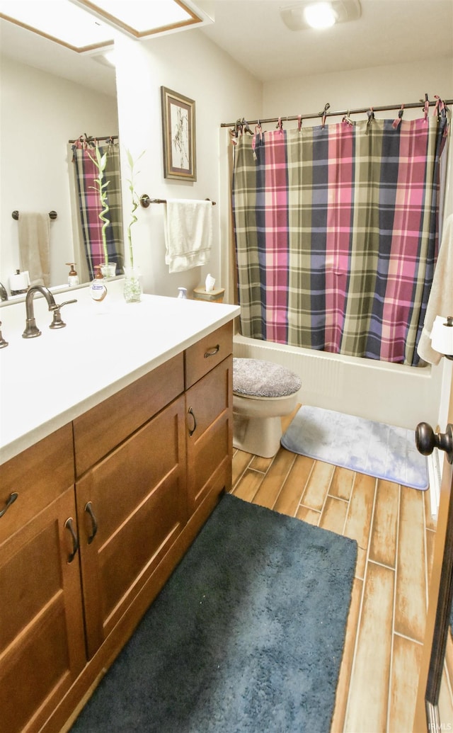 bathroom with wood finish floors, vanity, toilet, and shower / tub combo