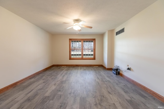 spare room with baseboards, wood finished floors, visible vents, and ceiling fan