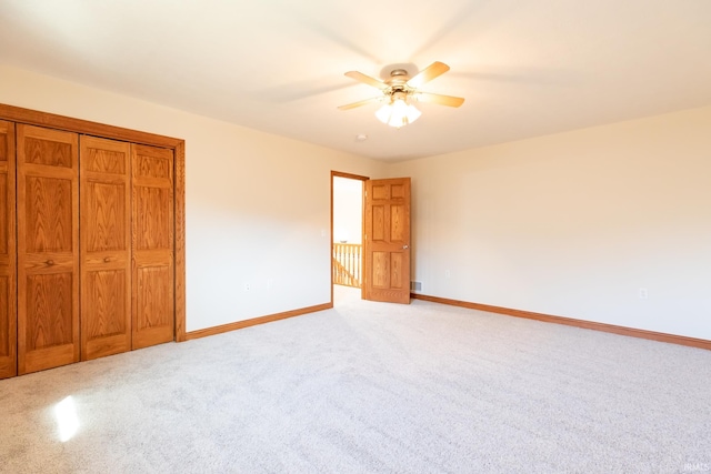 unfurnished bedroom with a closet, baseboards, light carpet, and ceiling fan