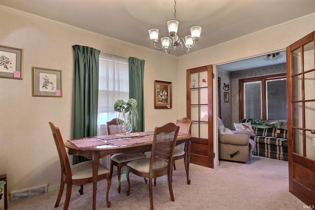 dining room featuring a notable chandelier, visible vents, light colored carpet, and ornamental molding