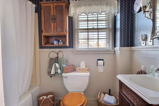 full bath featuring vanity, shower / bath combo with shower curtain, wainscoting, tile walls, and toilet