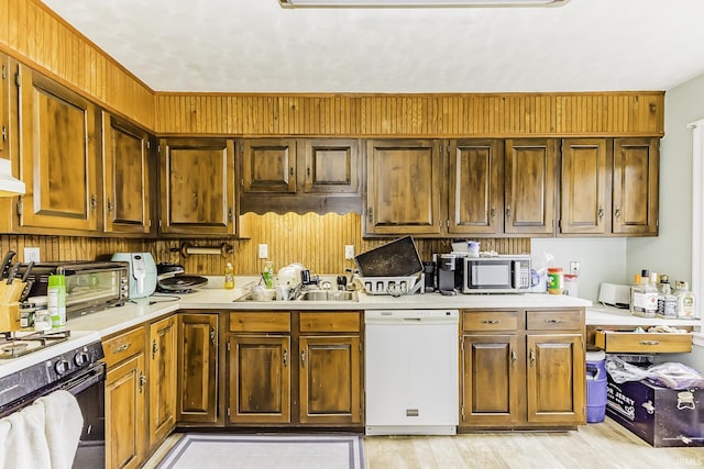 kitchen featuring stainless steel microwave, light countertops, range with gas stovetop, white dishwasher, and a sink