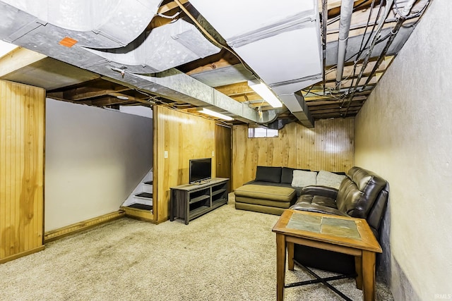 carpeted living area with wood walls and stairs