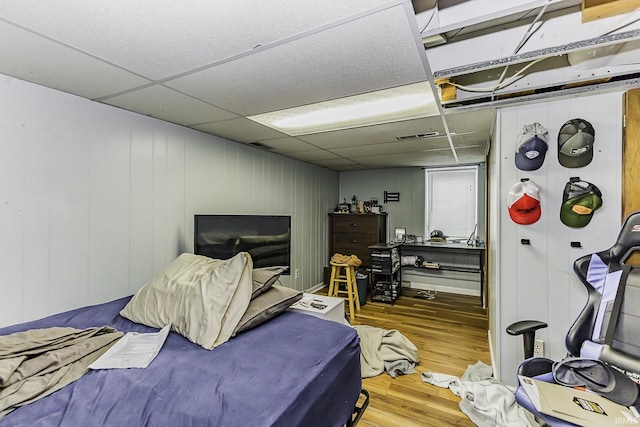 bedroom with wood finished floors, visible vents, and a paneled ceiling